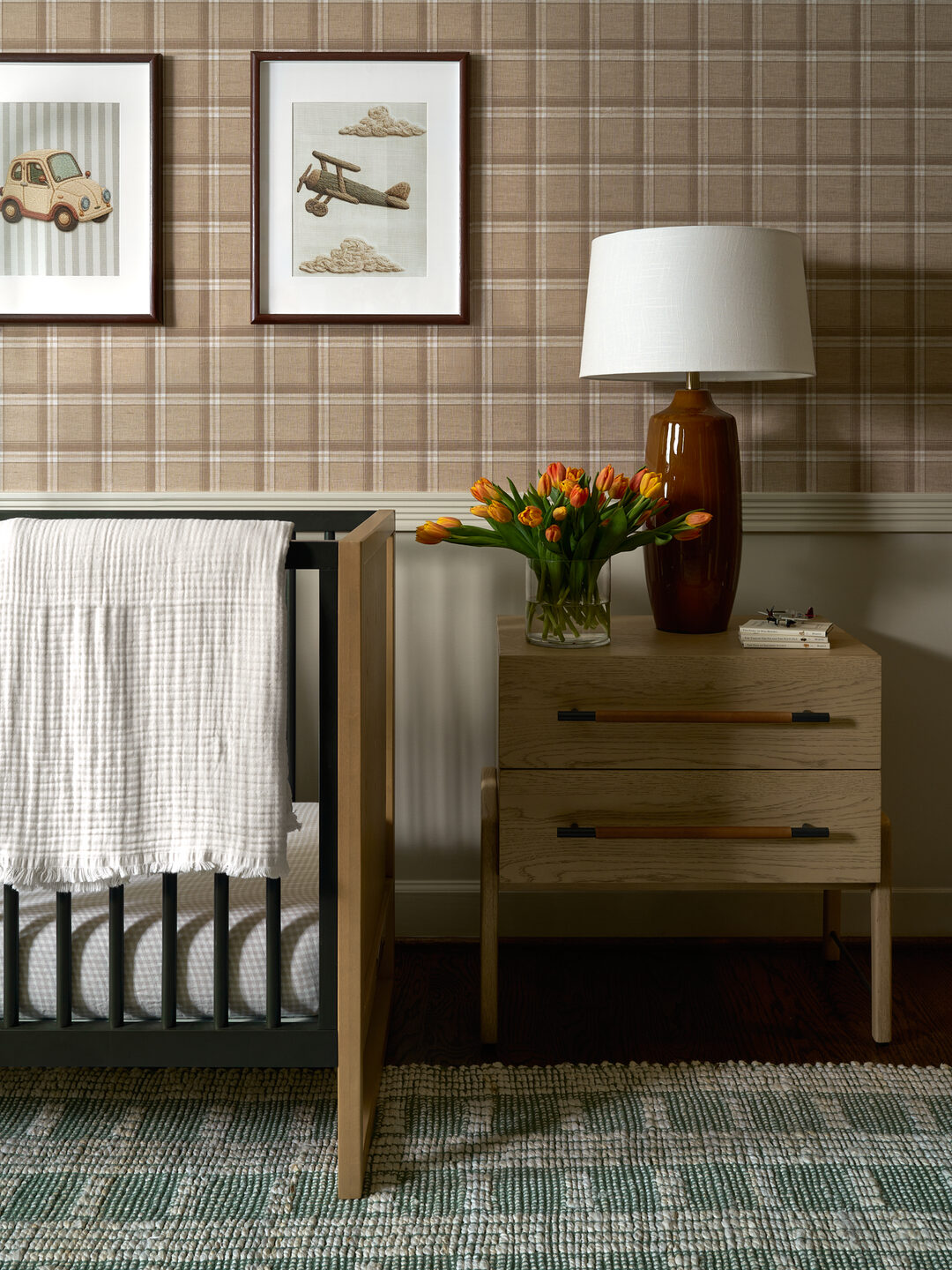 Millwood Road nursery crib detail with vintage transportation prints and oak dresser